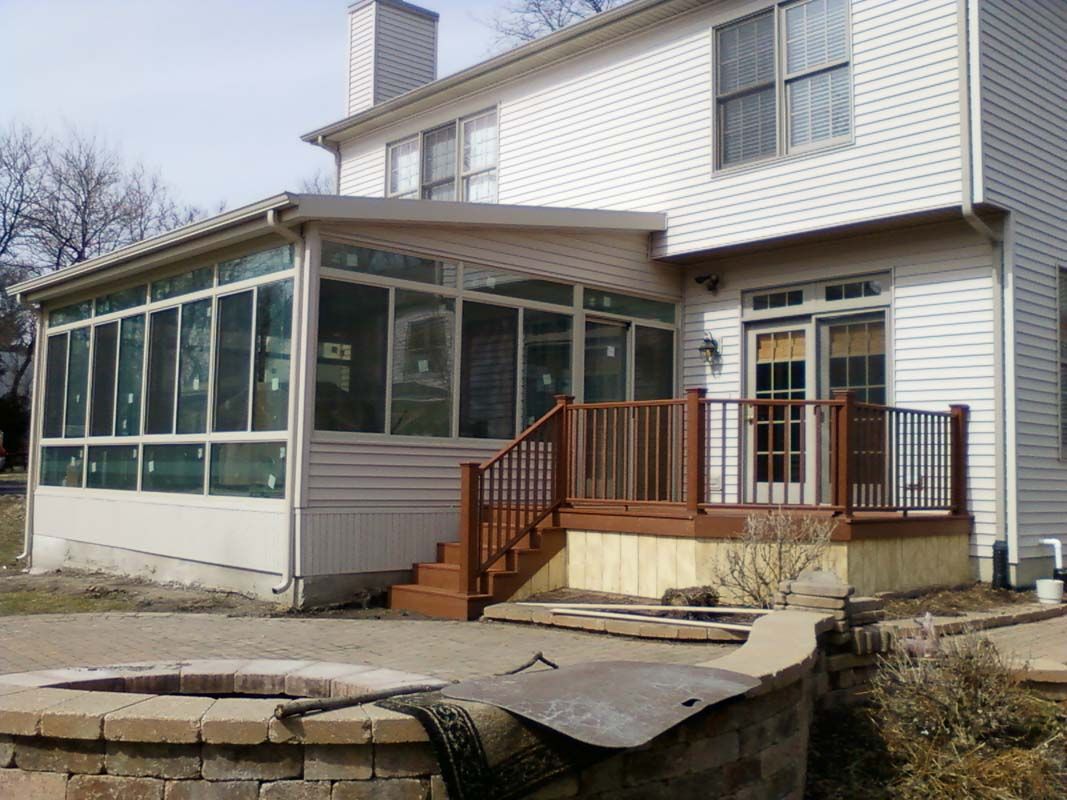 A white house with a sunroom and a deck