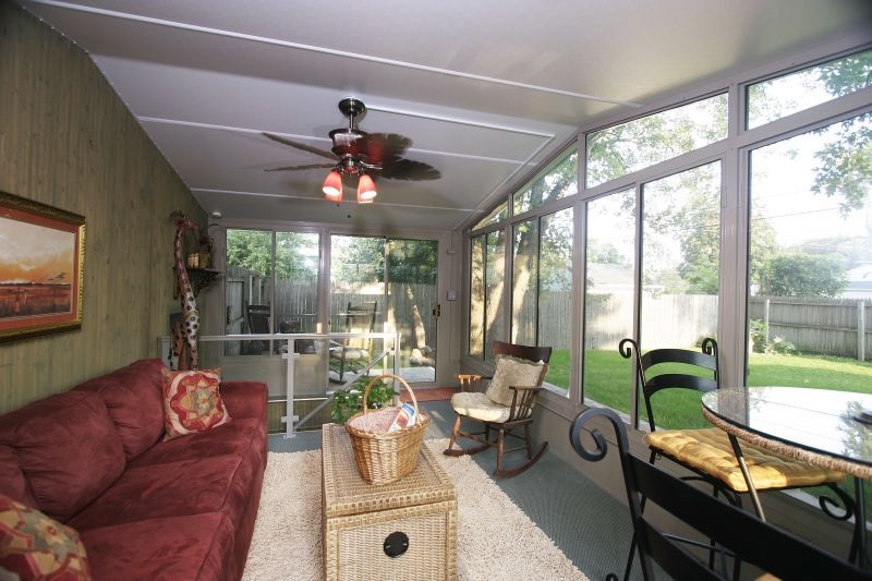 A living room with a couch , table , chairs and a ceiling fan.