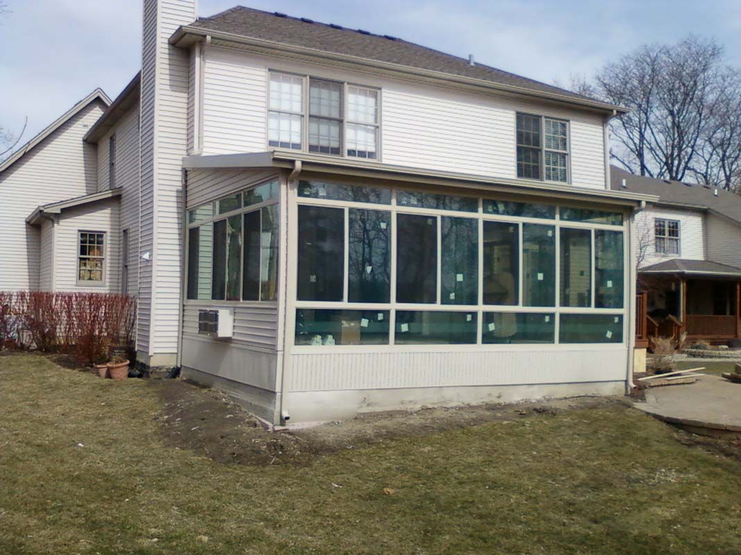 A house with a sunroom on the side of it.