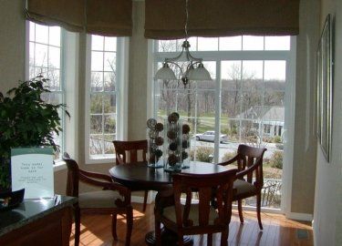 A dining room with a table and chairs and a large window