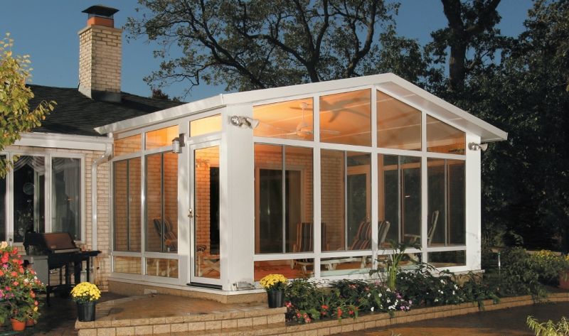 A house with a screened in porch that is lit up at night