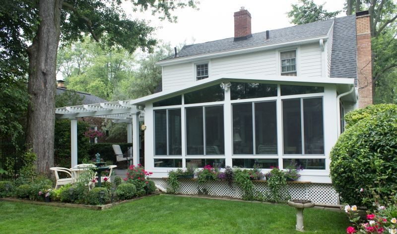A white house with a screened in porch in the backyard