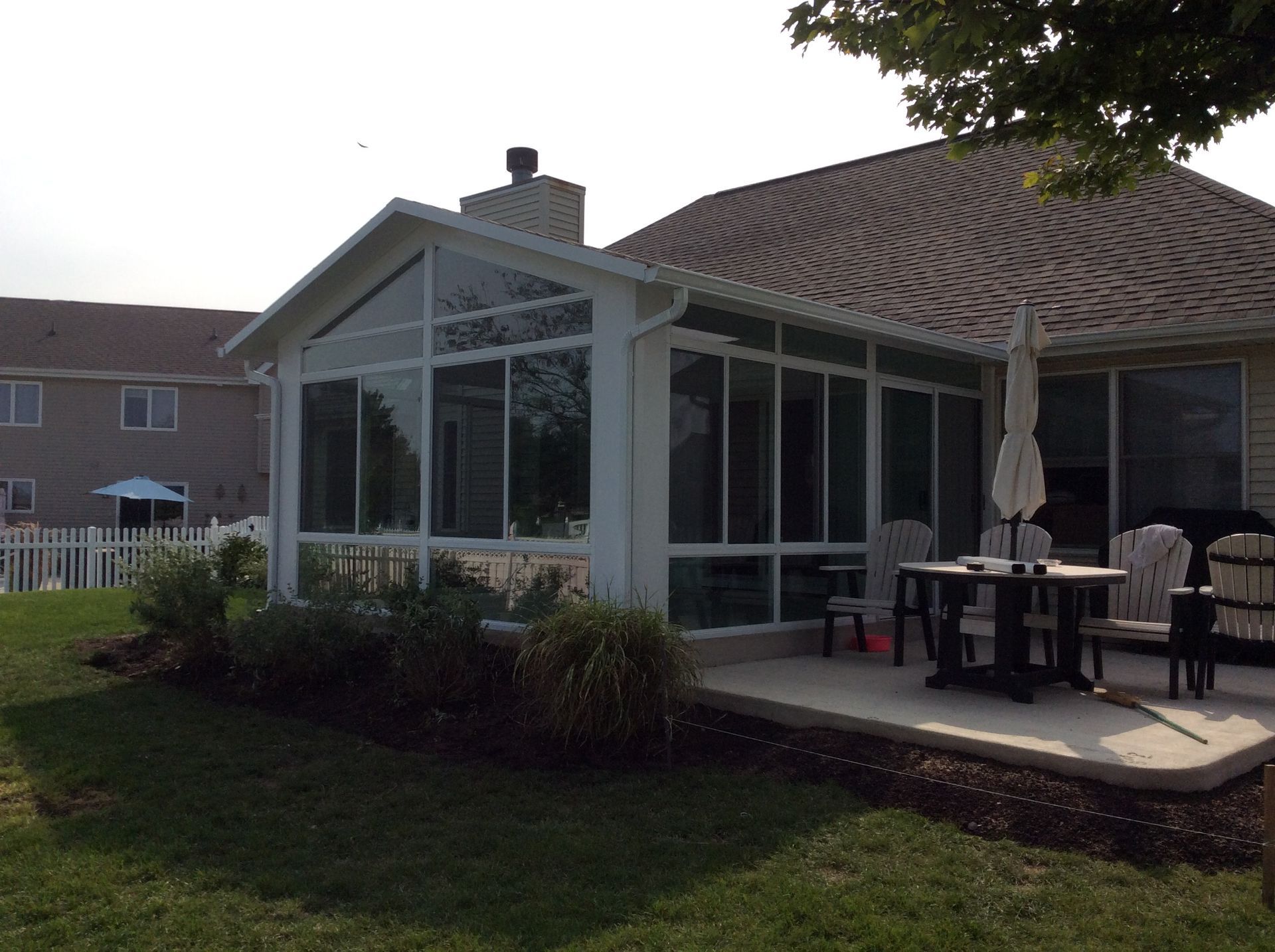 A house with a screened in porch with a table and chairs.
