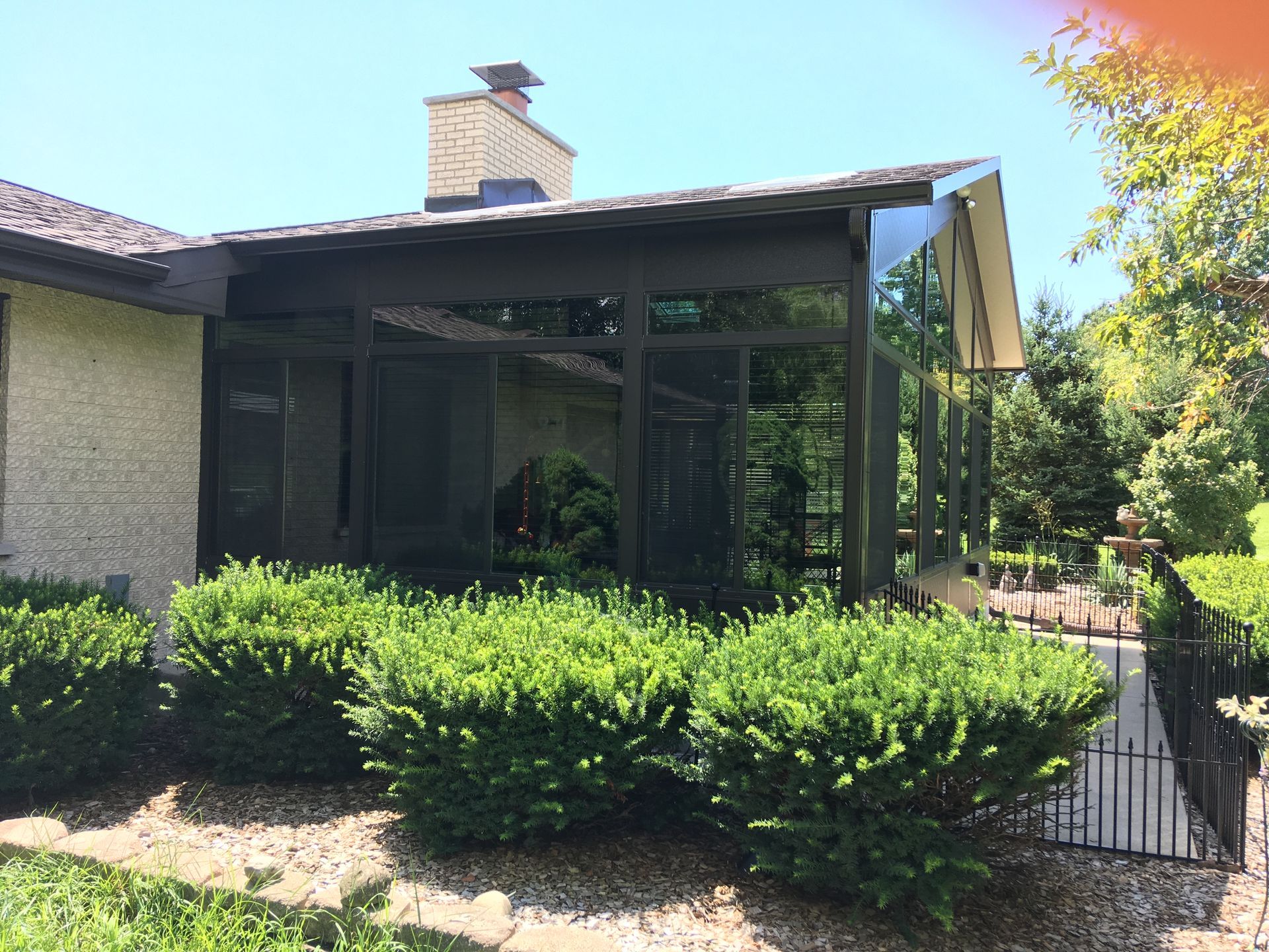 A house with a screened in porch and a fence in front of it.