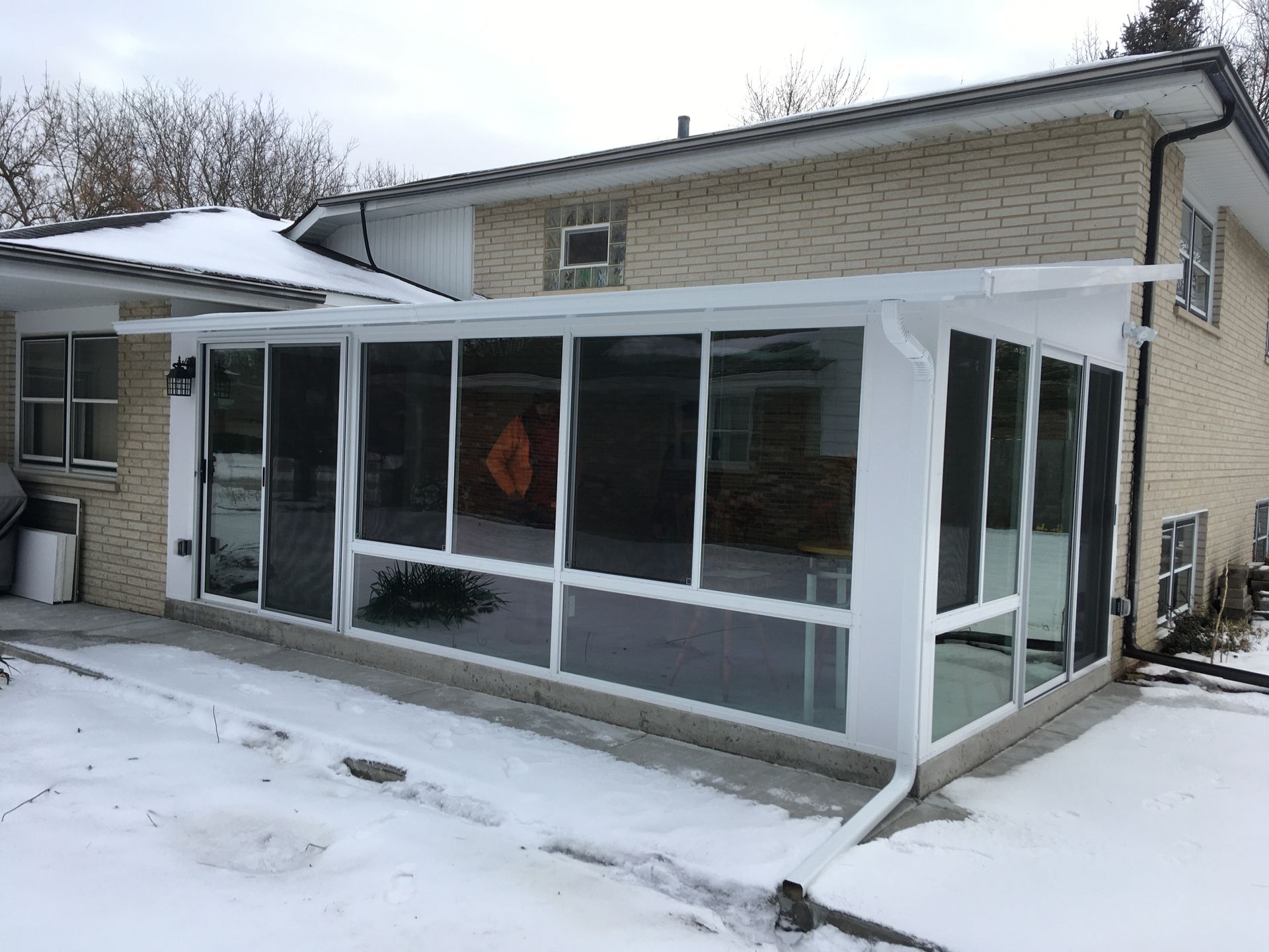A house with a screened in porch and snow on the ground.