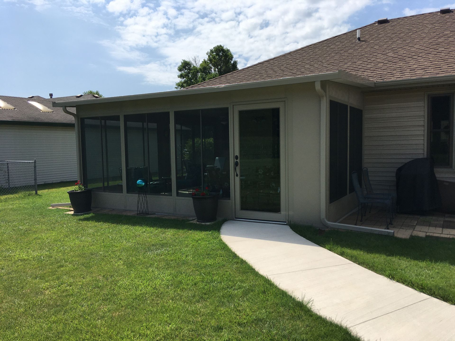 A house with a screened in porch and a walkway leading to it.
