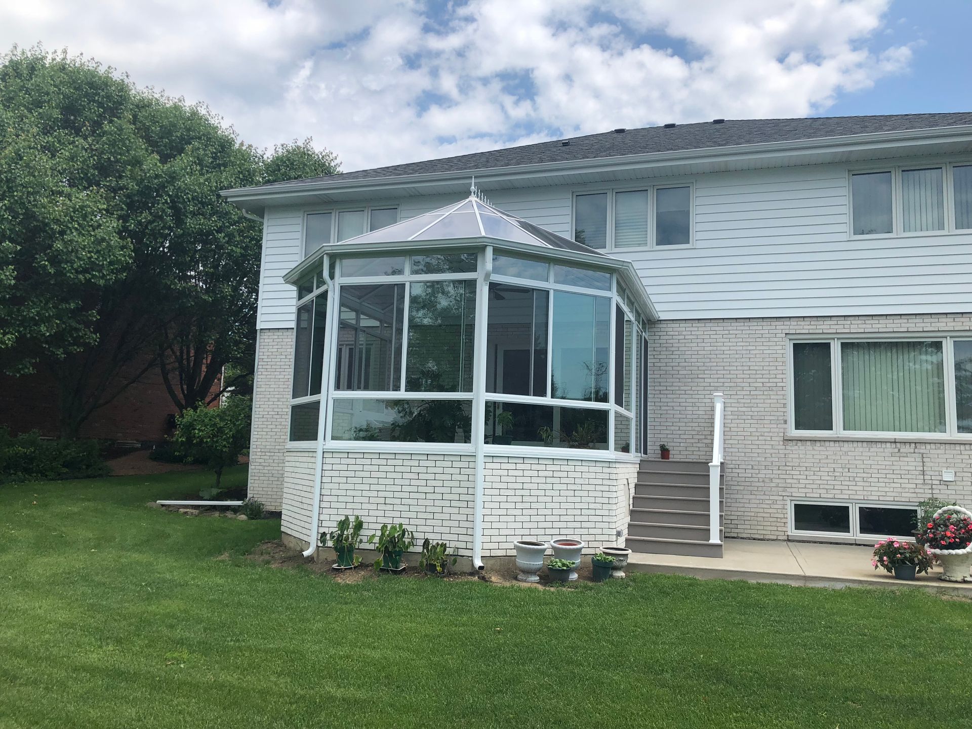 A white house with a screened in porch in the backyard.