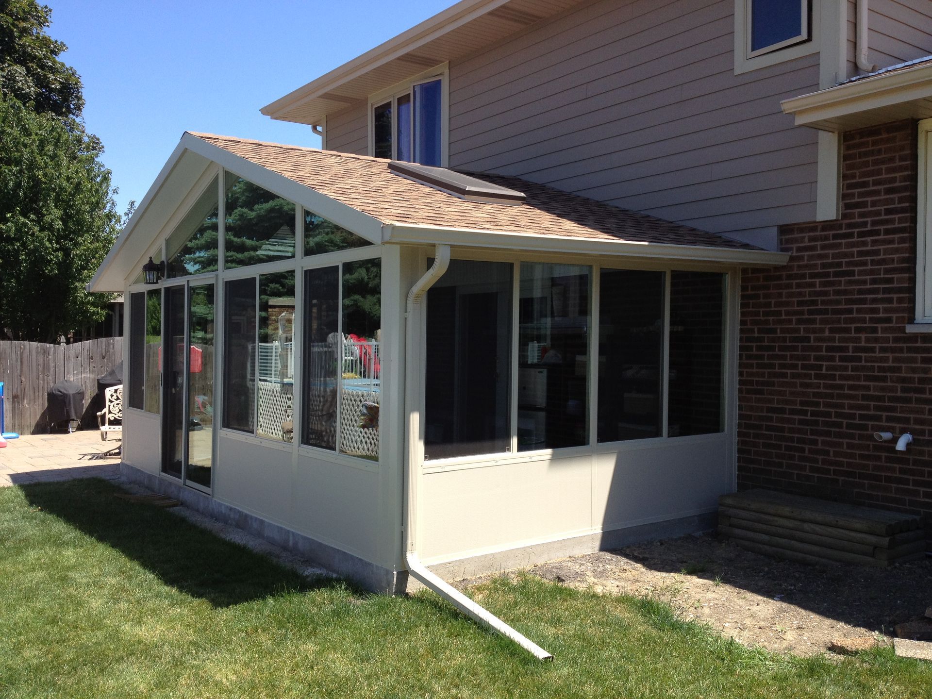 A screened in porch is attached to the side of a house.