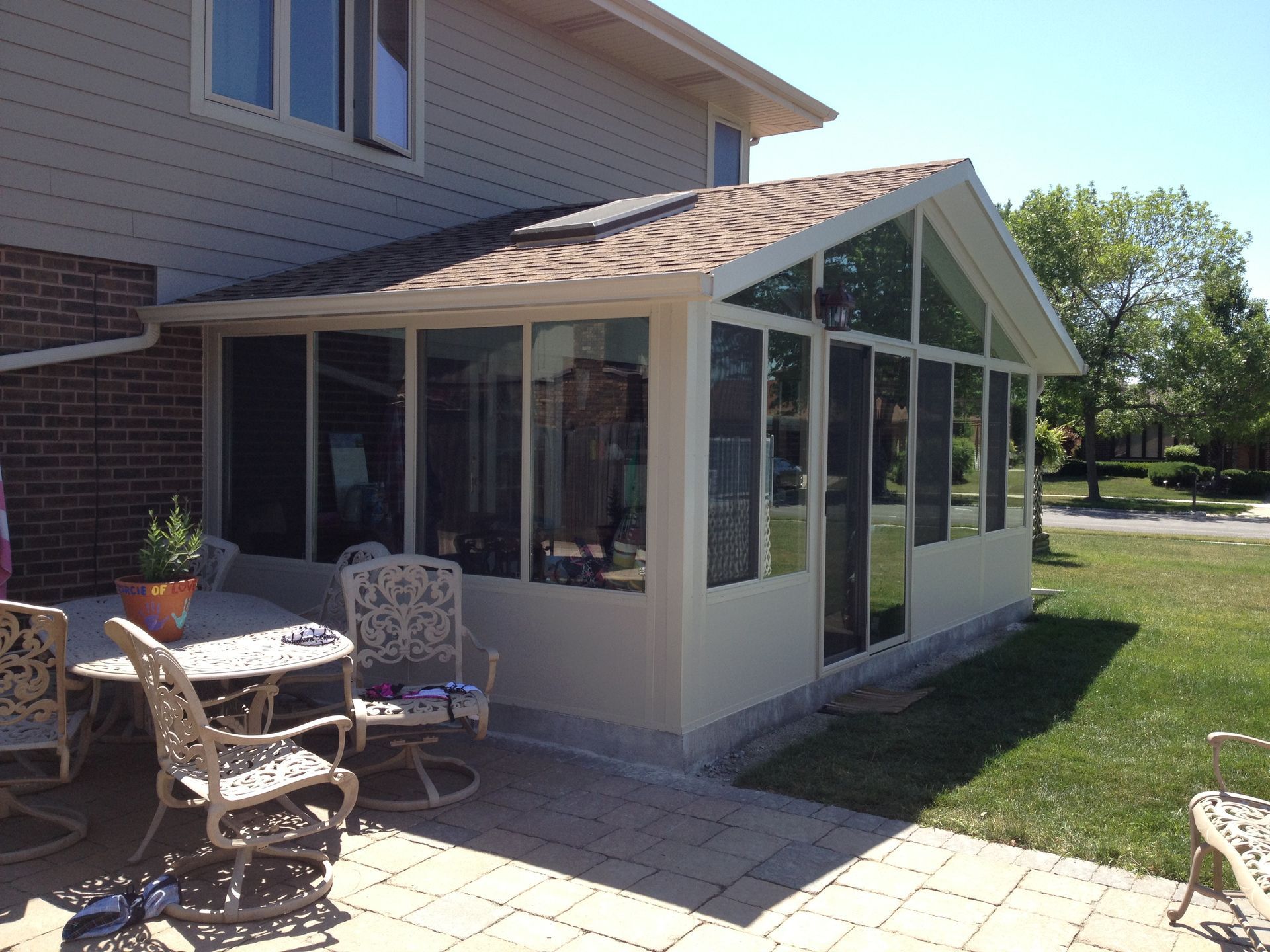 A house with a screened in porch with a table and chairs.