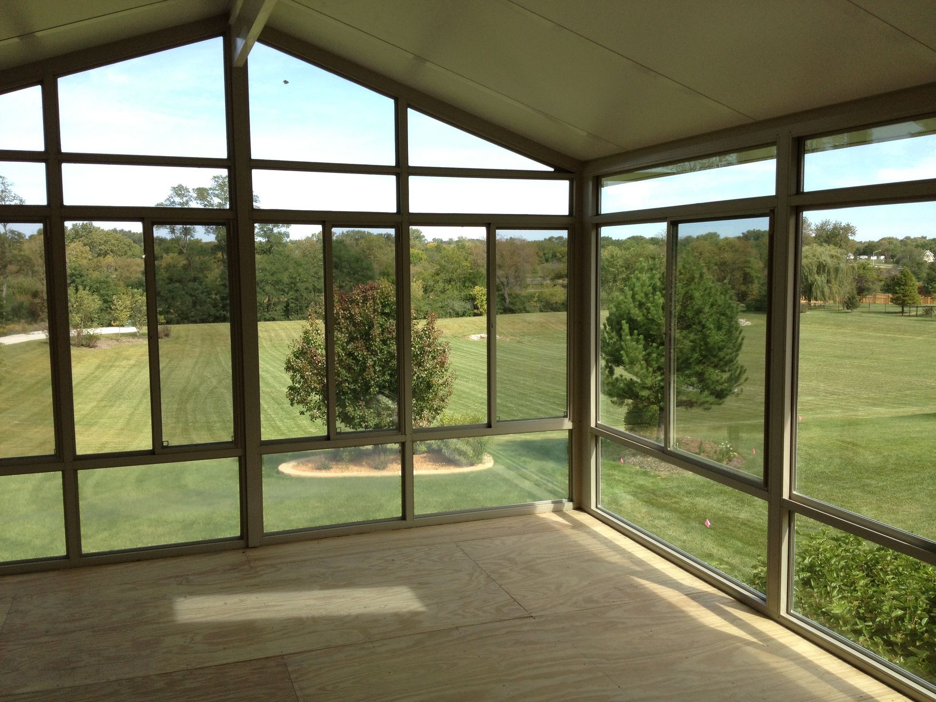 A screened in porch with a view of a golf course.