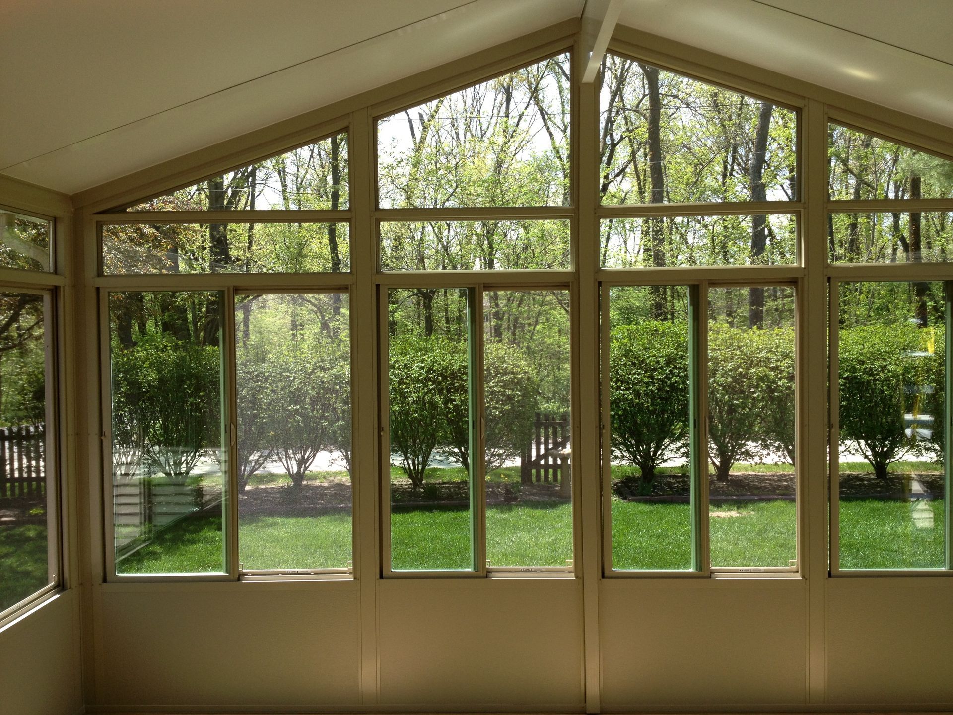 A sunroom with a lot of windows and trees in the background.