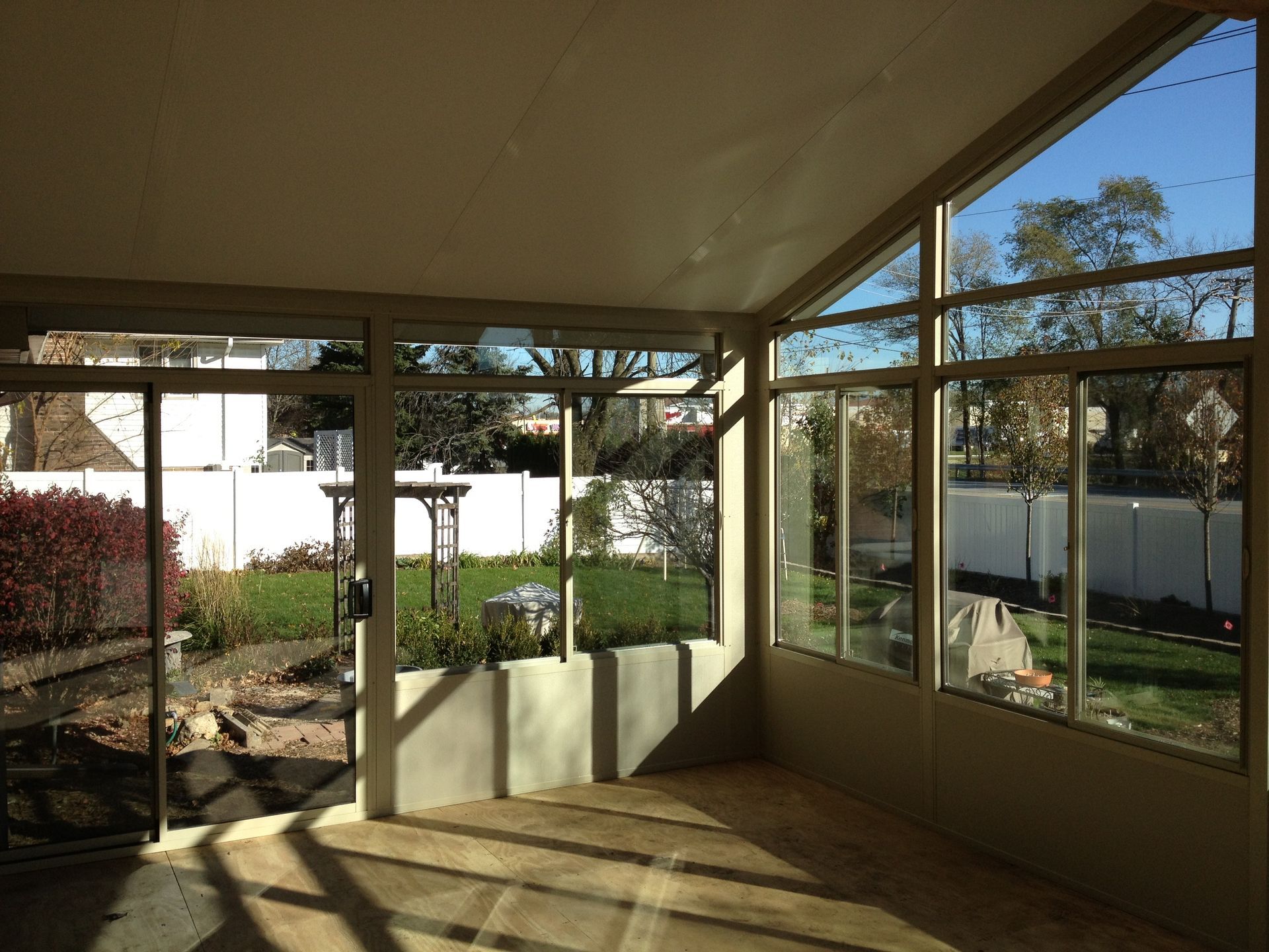 An empty room with a lot of windows and a patio in the background.