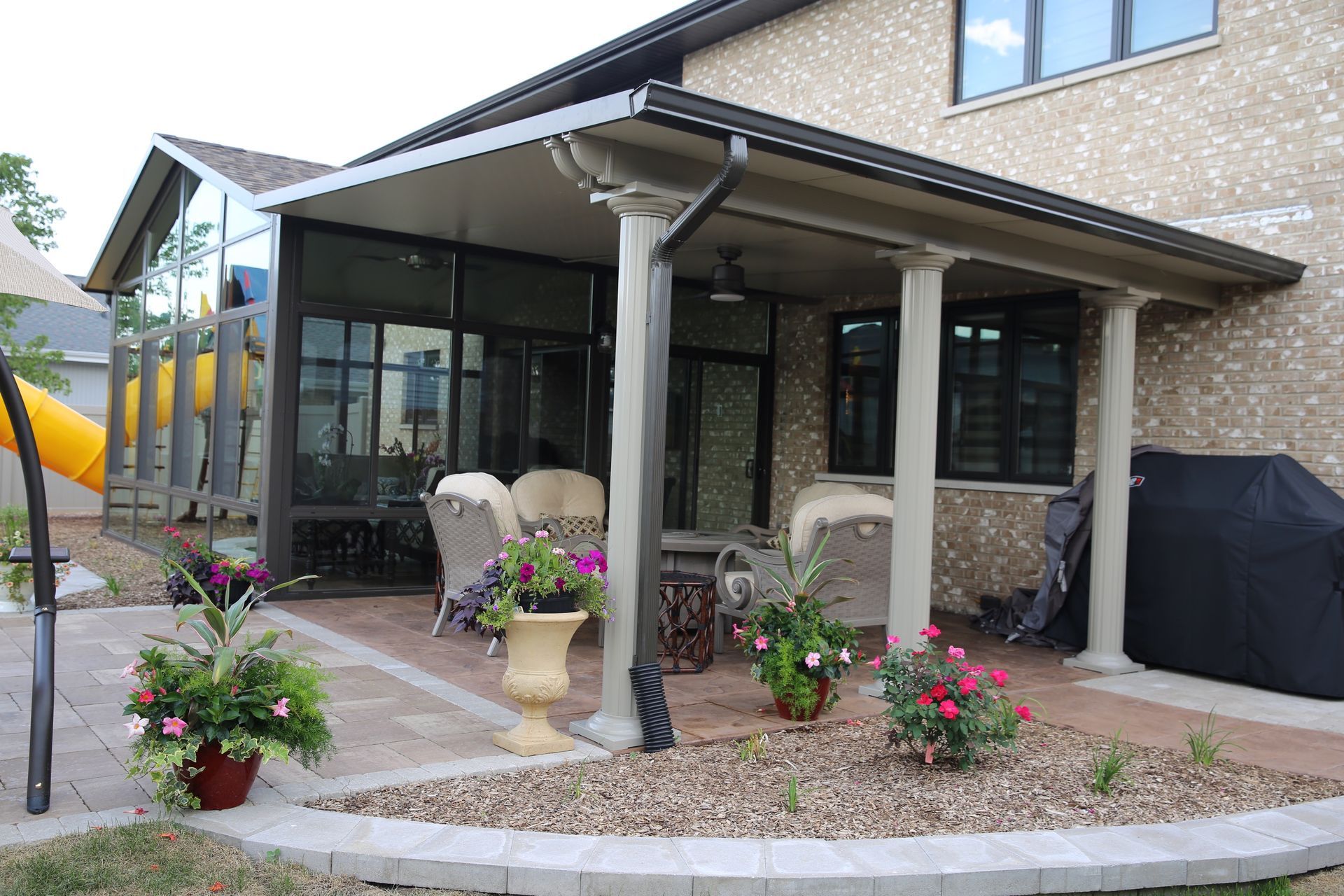 A house with a screened in porch and a playground in the background.