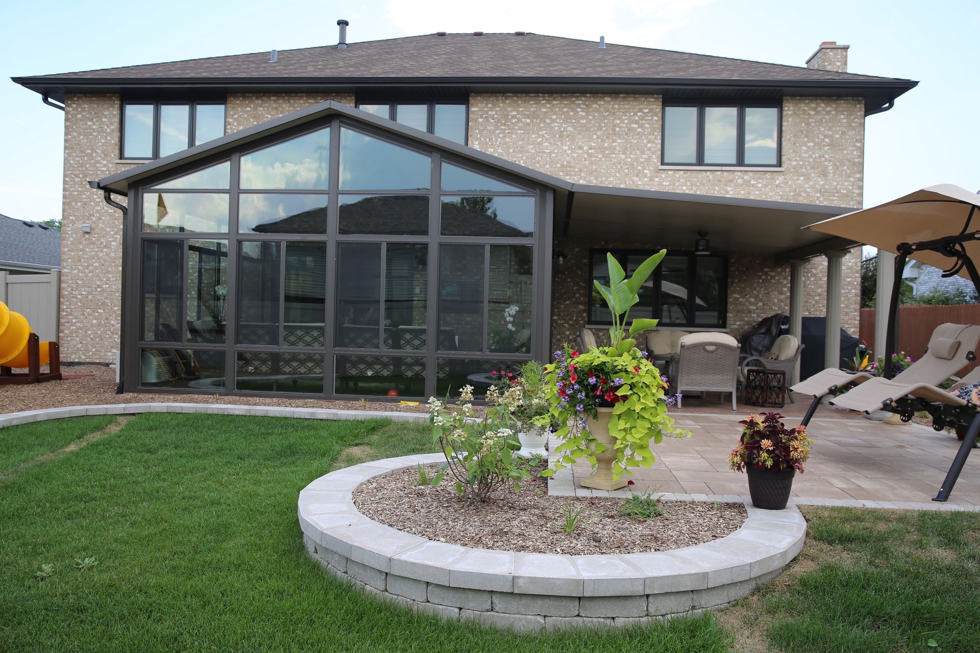 A large house with a sunroom and patio in the backyard.