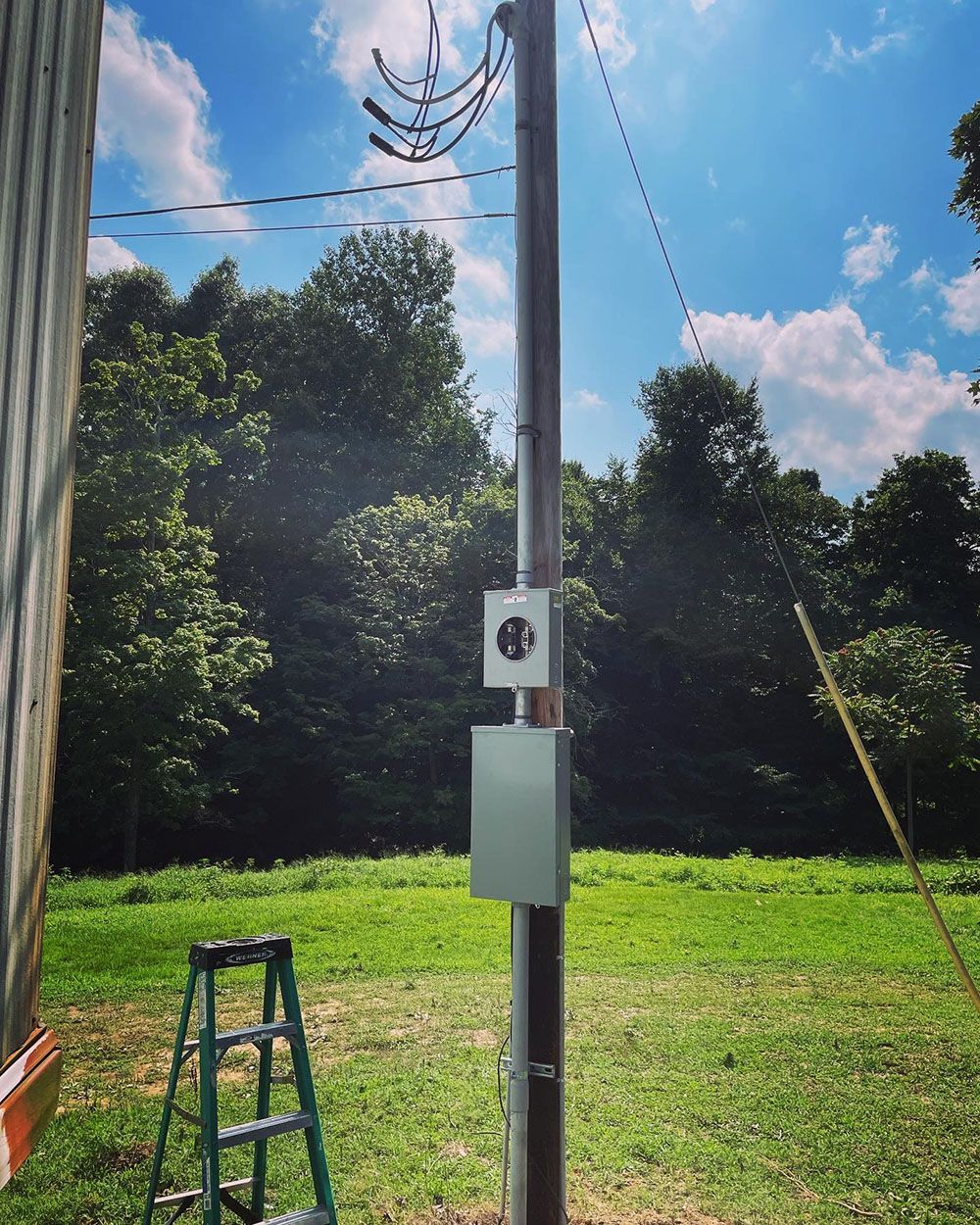 A ladder is leaning against a pole in a grassy field