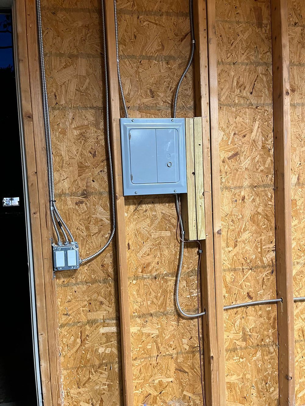 A wooden wall with electrical wires coming out of it.