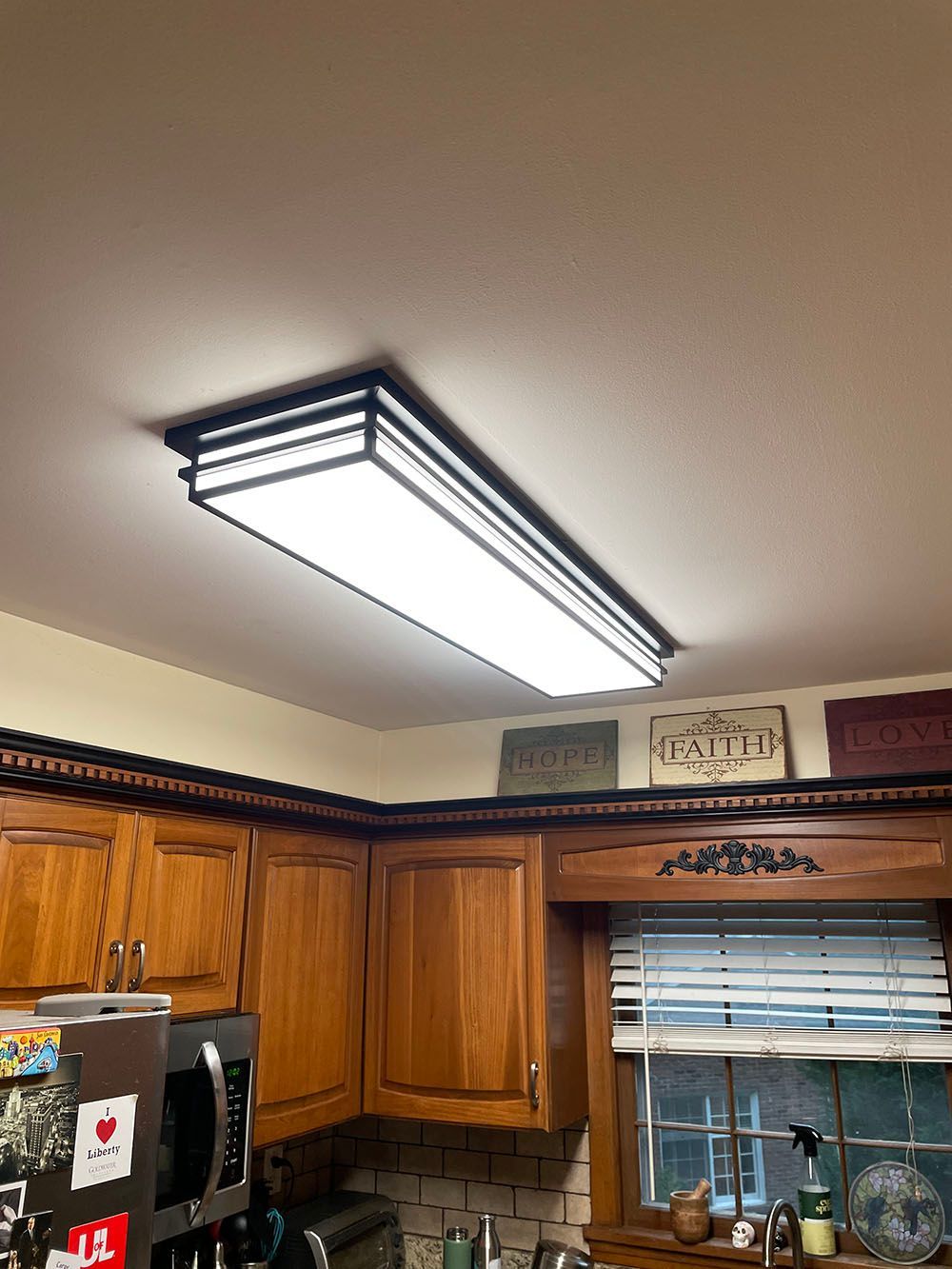 A kitchen with wooden cabinets and a ceiling light.