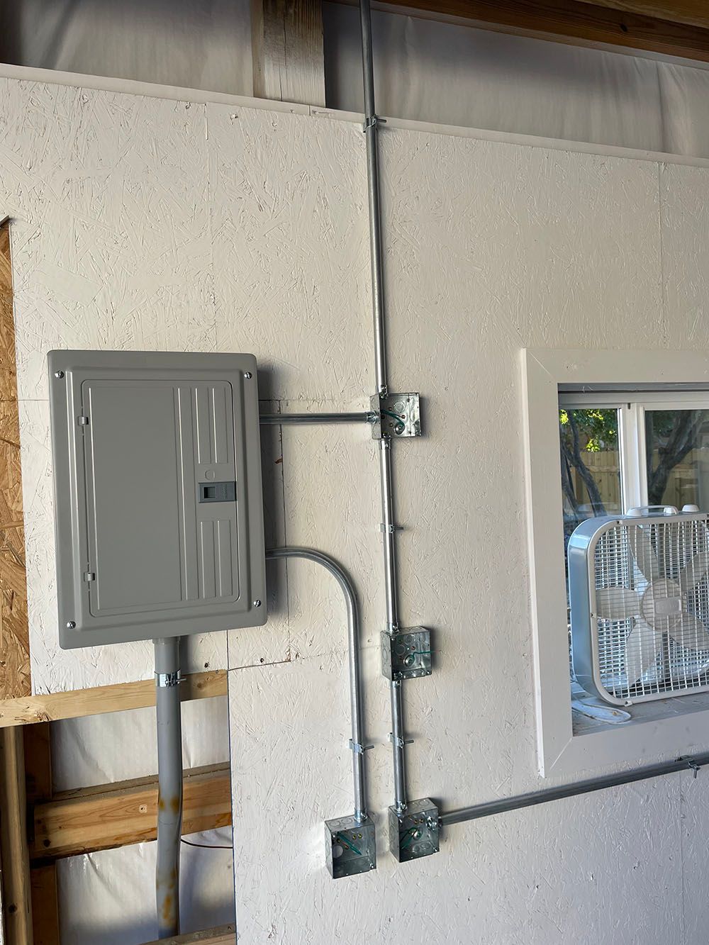 A gray box is sitting on a white wall next to a window.