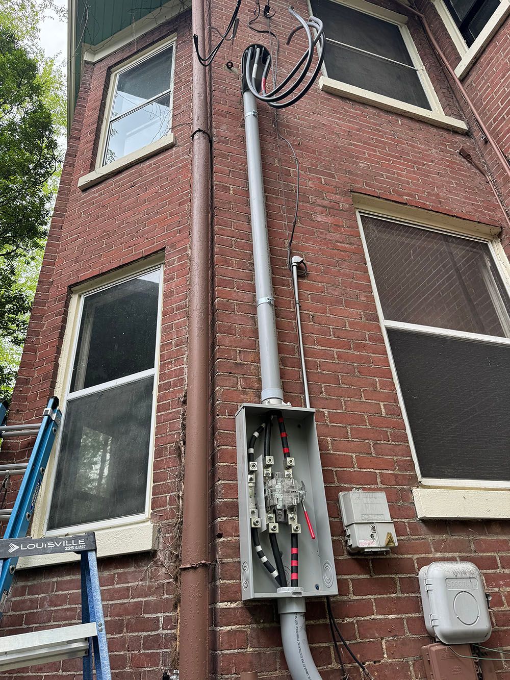 A ladder is sitting on the side of a brick building.