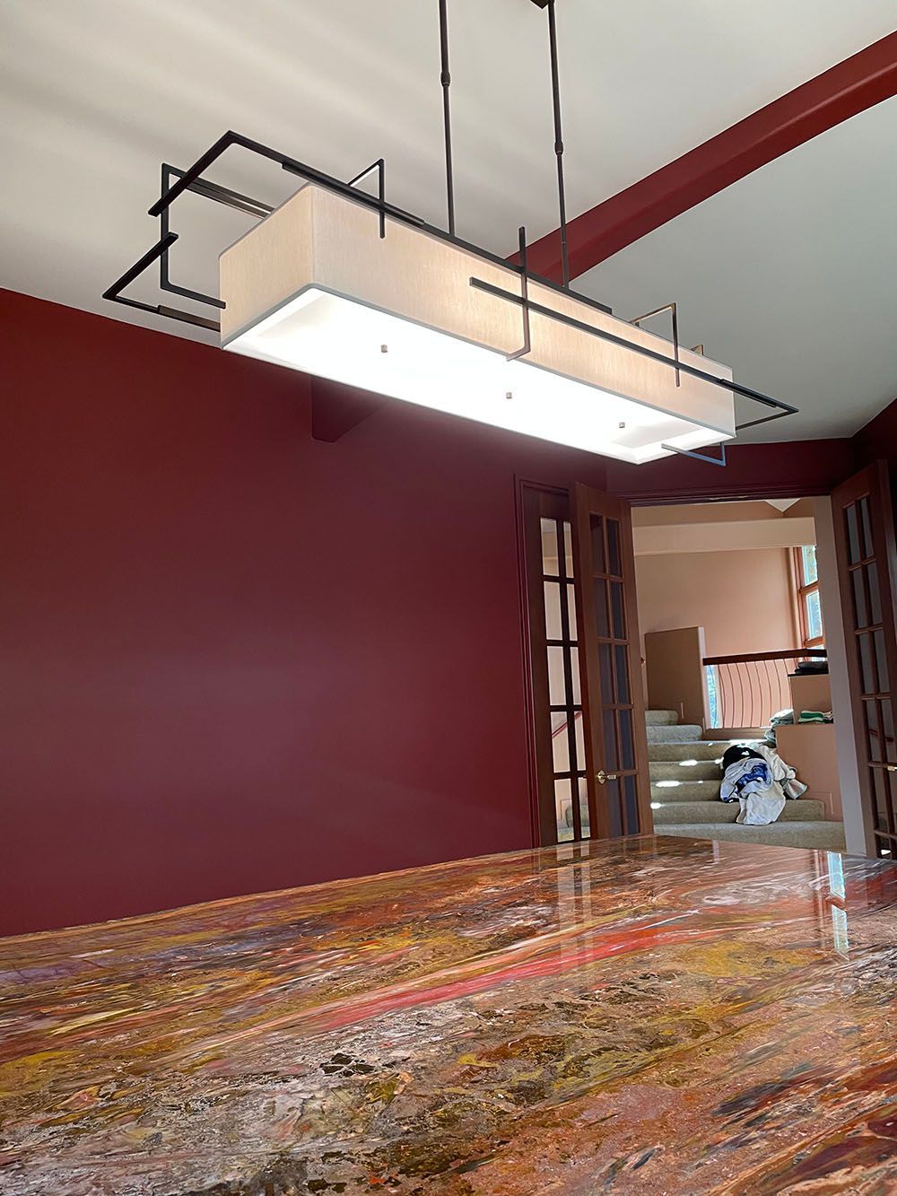 A dining room with a long chandelier hanging from the ceiling.