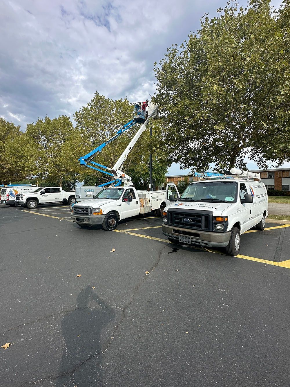 A group of utility trucks are parked in a parking lot.