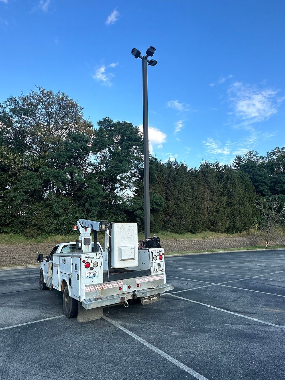 A white truck is parked in a parking lot next to a tall pole.