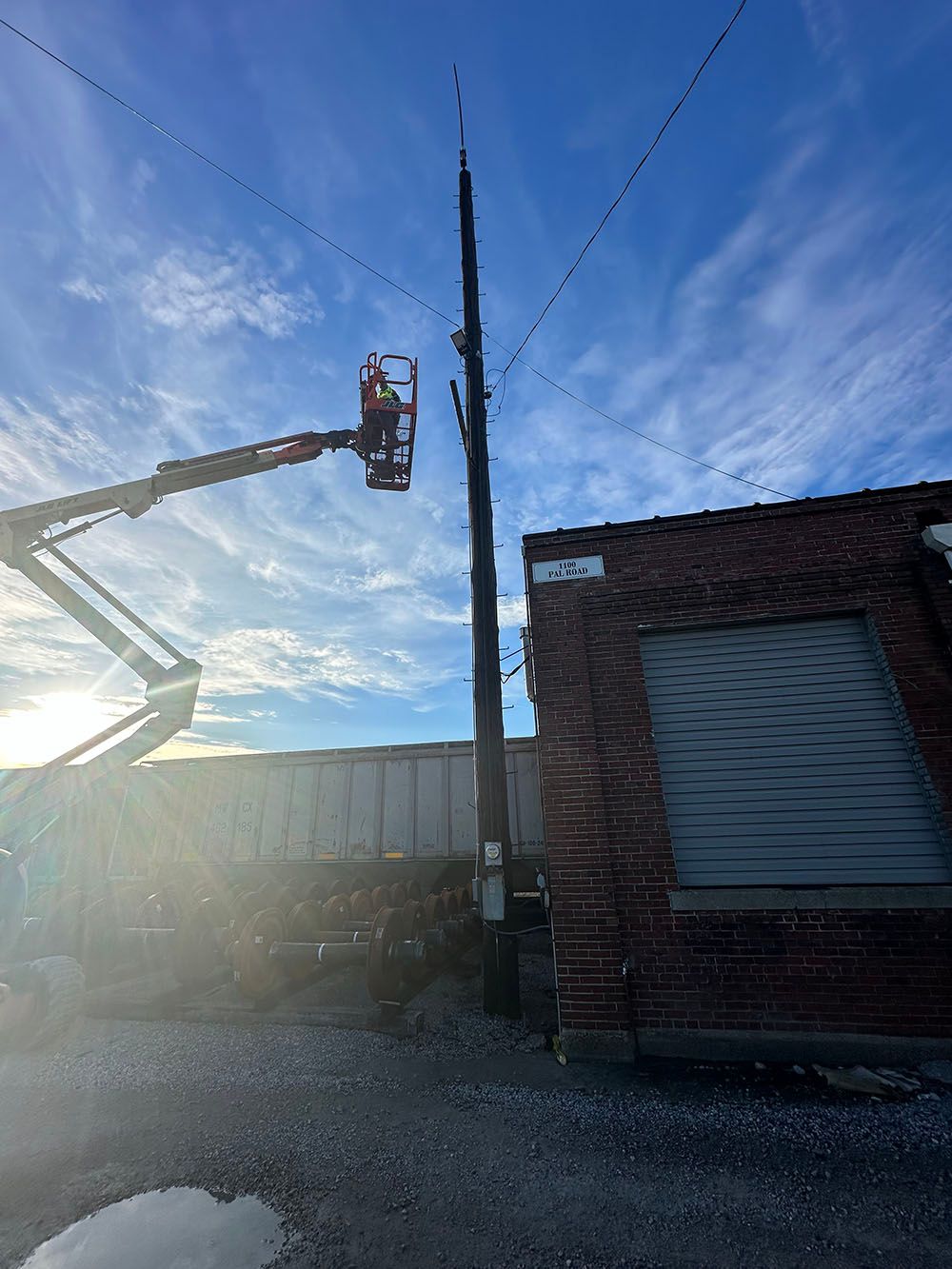 A man in a bucket is working on a telephone pole.