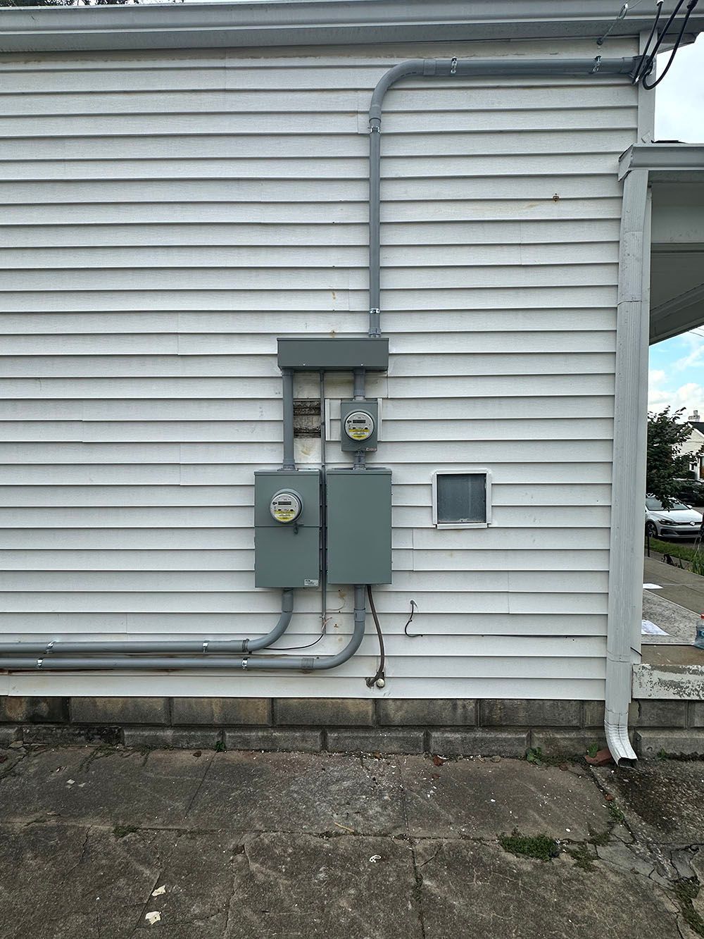 A white house with electrical boxes on the side of it.