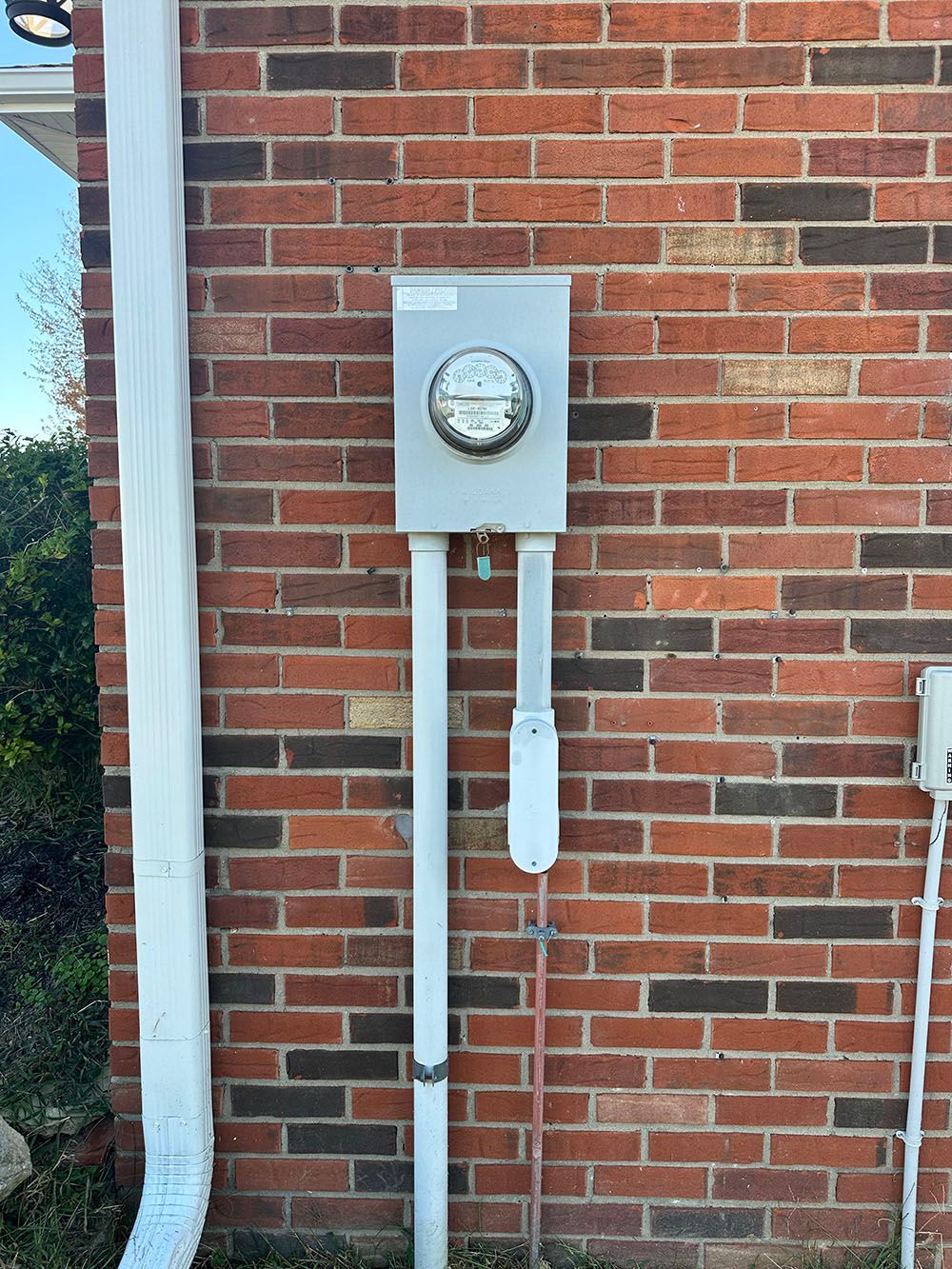 There is a meter on the side of a brick building.