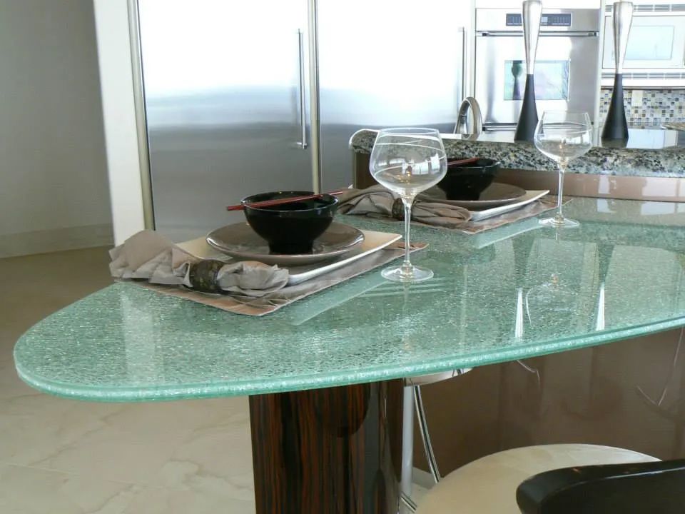 A kitchen island with place settings, glasses, and a textured green surface.
