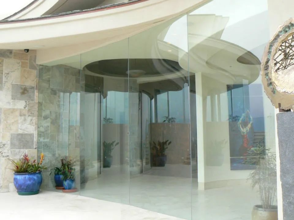 Glass-walled entrance of a modern building with potted plants and decorative accents.