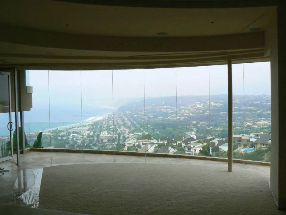 Interior view through large windows, overlooking a city and ocean on a hazy day.