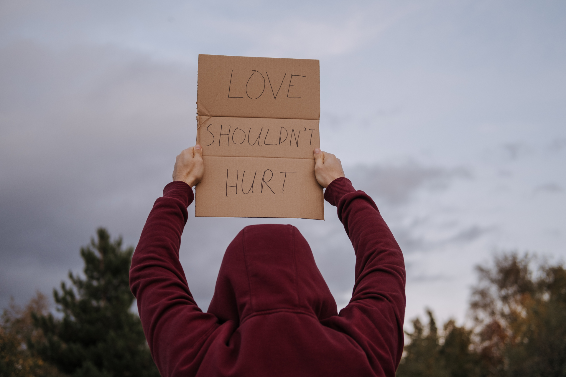 a person holding a sign that says love shouldn't hurt