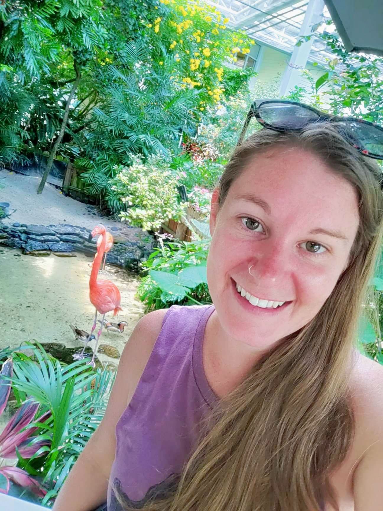 Ariel, a mental health intern, stands with a  a colorful flamingo in the background, symbolizing tranquility and renewal.