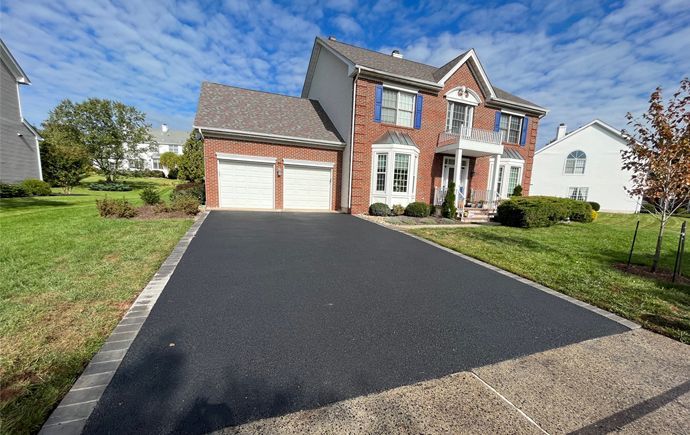 A large brick house with a black driveway in front of it.