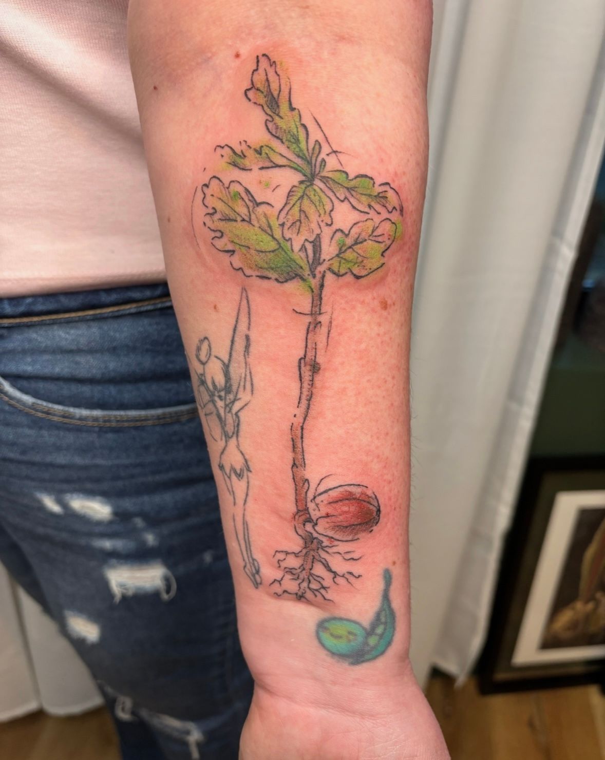 A woman has a tattoo of a tree growing out of a seed
