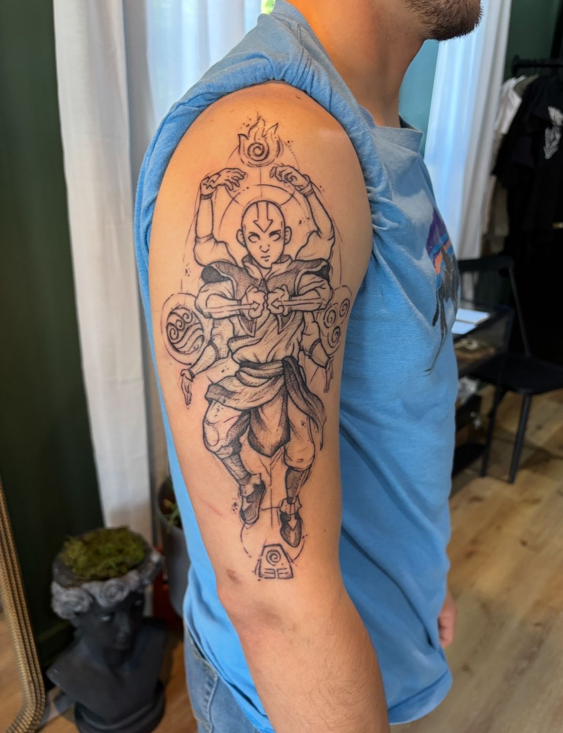 A man has a tattoo of avatar aang on his arm.