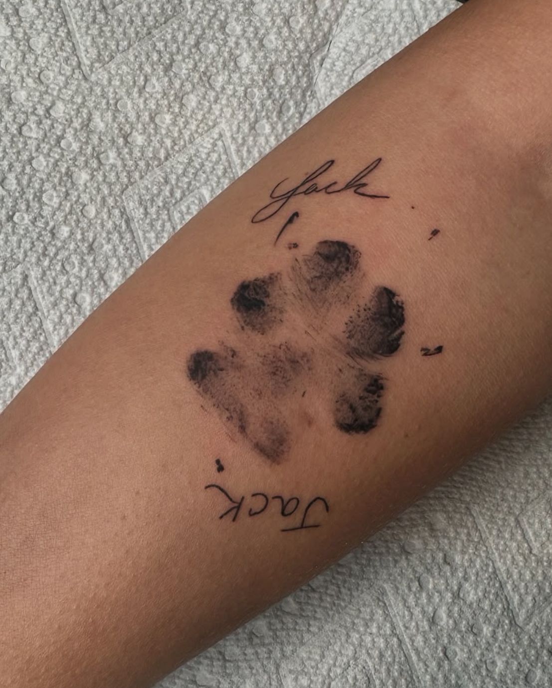 A person has a tattoo of a paw print and the name jack