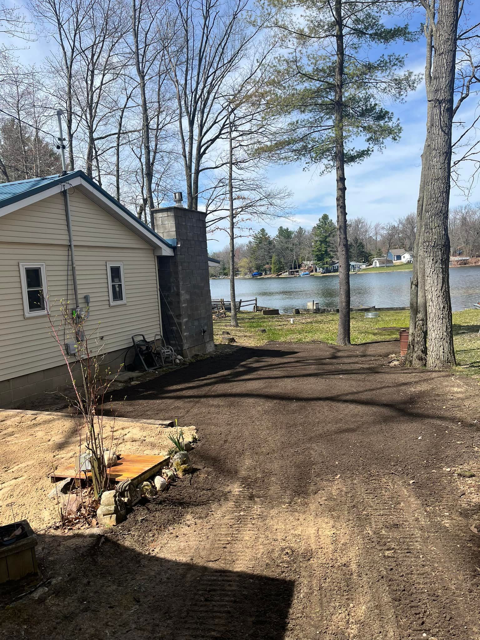 Black Dirt Driveway next to house in woods. 