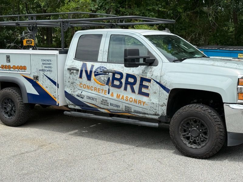 White NOBRE service pickup truck with ladder rack parked on a driveway, side view