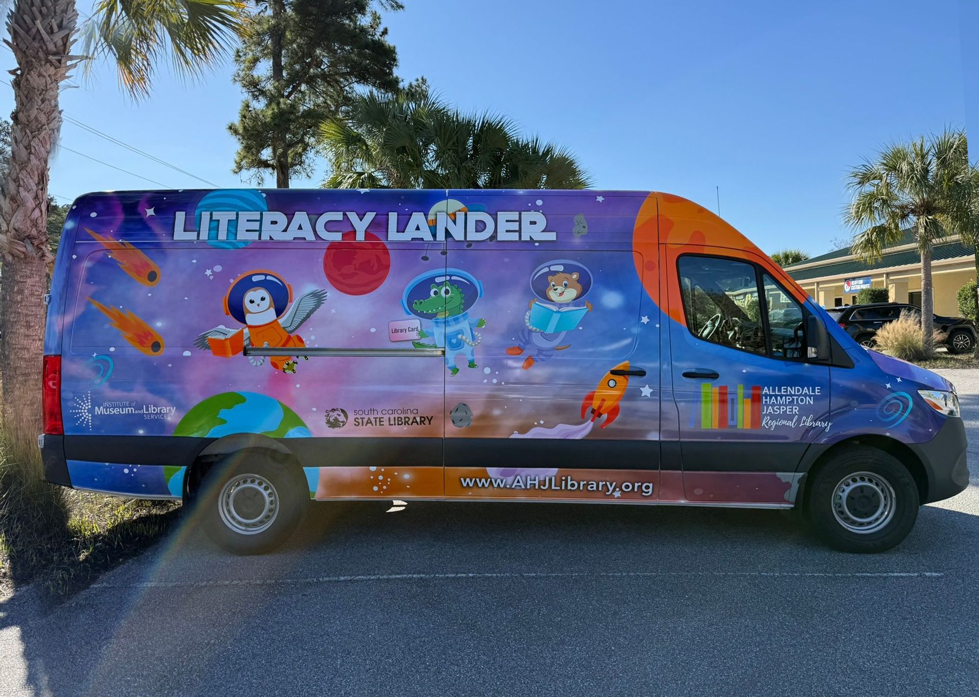Colorful Literacy Lander van parked outdoors with cartoon reading graphics and bright rainbow accents