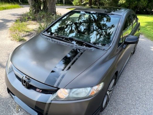 Gray Honda Civic coupe with black racing stripes on asphalt.