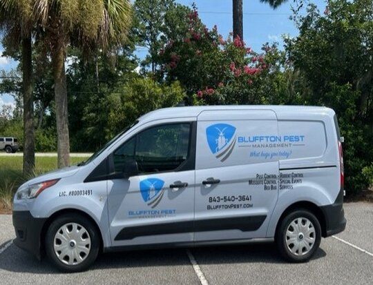 Gray van with Bluffton Pest Management logo parked outdoors.