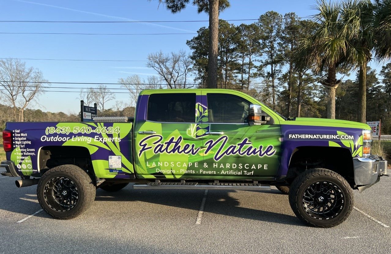 Green and purple Father Nature landscaping truck with black wheels parked outside.