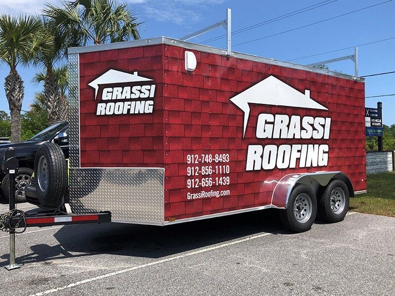 Grassi Roofing trailer with red brick design, logo, and contact information.