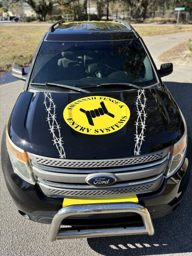 Black Ford Explorer with a yellow logo and barbed wire design on the hood, parked outside.