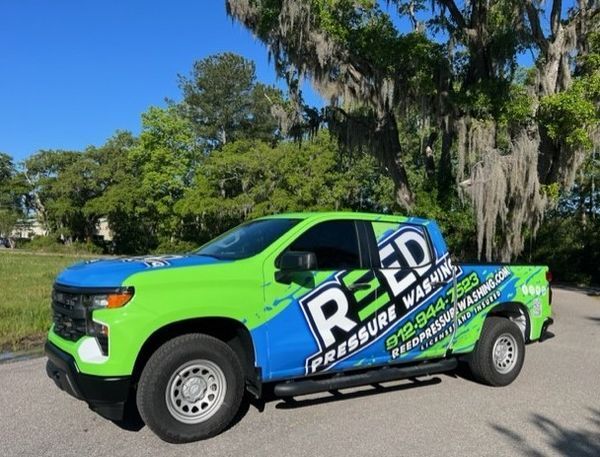 Green and blue Chevrolet truck with Reed Pressure Washing logo on road.