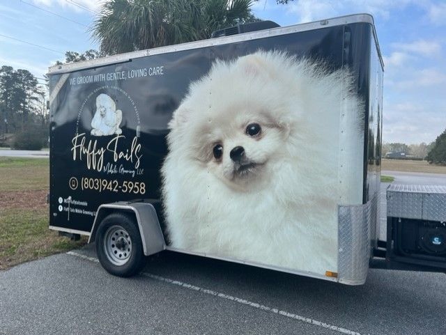 Mobile dog grooming trailer with a large fluffy white dog image; 