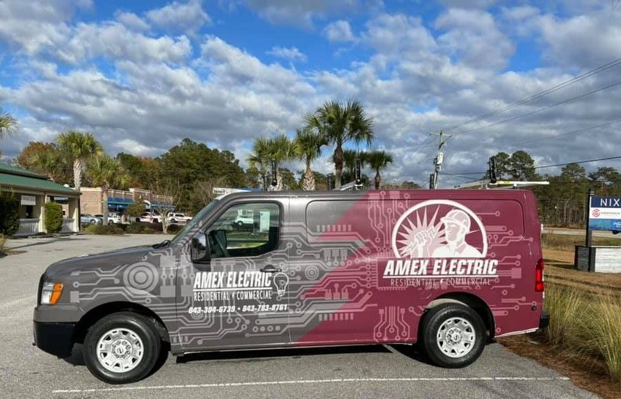 Gray Amex Electric van with electrical circuit graphics parked in front of a building on a sunny day.