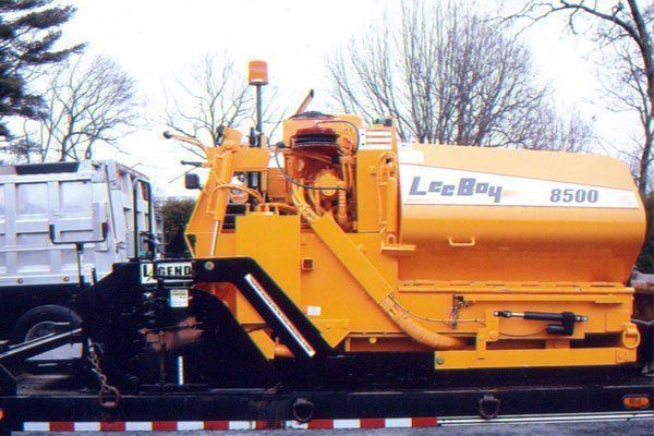 A yellow legboy 8500 asphalt paving machine is parked on the side of the road